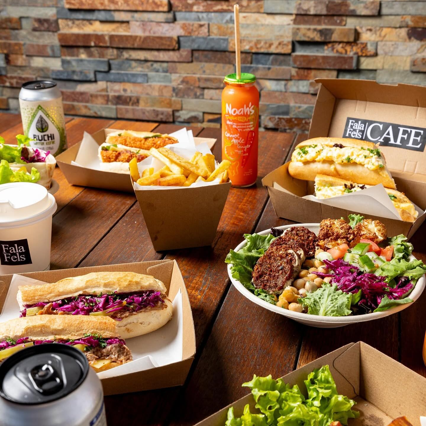Fala Fels baguettes, chips, Noah's juice, Buchi kombucha and a falafel salad on the stone-wall table